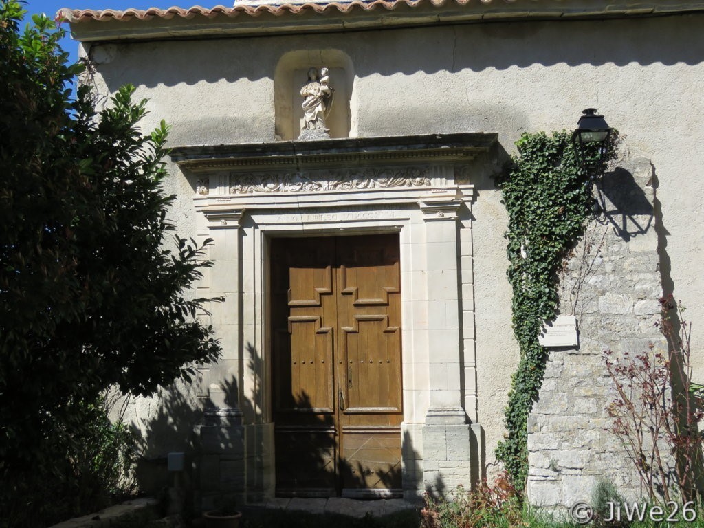 Entrée de l'église décorée surmontée d'une frise corniche et d'une statue de la Vierge à l'enfant